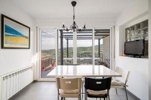 ein Esszimmer mit einem Tisch und Stühlen sowie einem großen Fenster in der Unterkunft ENTREPINOS Chalet sierra Madrid piscina privada+WiFi GRN423 in Rozas de Puerto Real