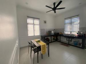 a kitchen with a table and a ceiling fan at ARRA Guest House, Pantai Cahaya Bulan, Kota Bharu in Kota Bharu