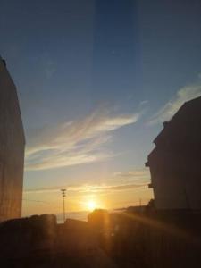 un coucher de soleil dans une ville avec le soleil dans le ciel dans l'établissement Rest House - Vila do Conde, à Vila do Conde