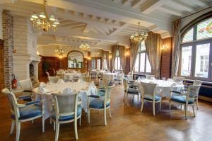 une salle à manger avec des tables et des chaises blanches dans l'établissement Hôtel de L'univers, à Arras