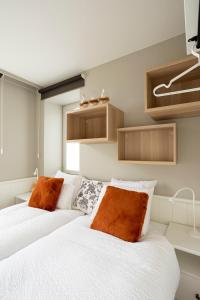 two beds in a bedroom with white sheets and orange pillows at Enjoytoday vakantiewoning 45 in Oudenaarde