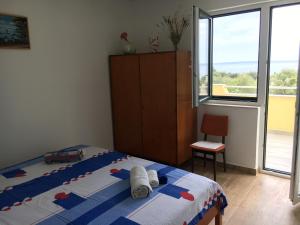 a bedroom with a bed and a chair and a window at APARTMENT ŽUŽI Otok Silba Hrvatska in Silba