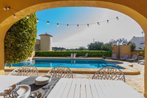 Un patio con mesa y sillas y una piscina. en Villa Mandarina - Costa CarpeDiem, en Calpe