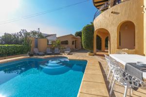 een zwembad met een tafel en stoelen naast een huis bij Villa Mandarina - Costa CarpeDiem in Calpe
