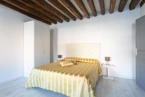 ein Schlafzimmer mit einem Bett mit einer gelben und weißen gestreiften Decke in der Unterkunft Canaletto Apartment Rialto in Venedig
