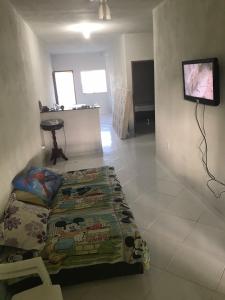 a living room with a bed and a flat screen tv at Casa agradável em Guriri - Rua 17 Norte in São Mateus