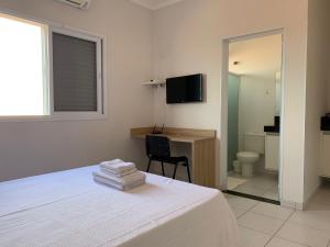 a bedroom with a bed and a desk and a television at Spazio Italian Lofts in Paulínia