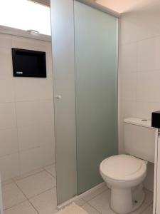 a bathroom with a toilet and a glass shower door at Spazio Italian Lofts in Paulínia