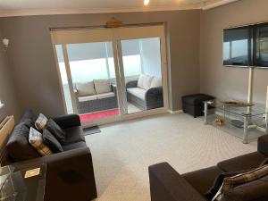 a living room with two couches and a sliding glass door at Palmbeach Place in Kent