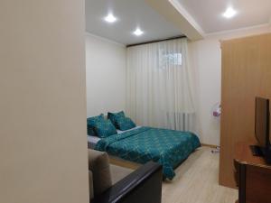 a bedroom with a bed and a couch and a television at Апартамент в курзоне пр Кирова 7 in Pyatigorsk