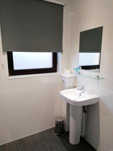 a bathroom with a white sink and a window at Premier Lodge in Falkirk