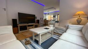 a living room with white furniture and a flat screen tv at Charming Sea Side Sun Apartment in Hermanus