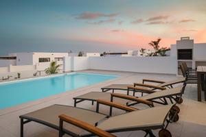 een zwembad met ligstoelen en een zwembad bij Villas Altos de Lanzarote in Playa Blanca