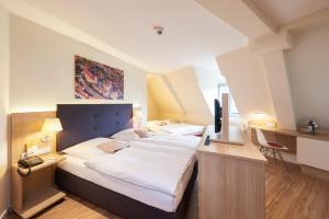 a bedroom with a bed and a desk with a television at Hotel VICTORIA Nürnberg in Nuremberg +59 photos