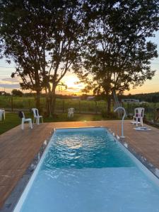 a pool with chairs and a sunset in the background at Solar das Aroeiras in Serra do Cipo