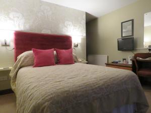 a bedroom with a large bed with two red pillows at The Bay Horse Hotel And Restaurant in Ulverston