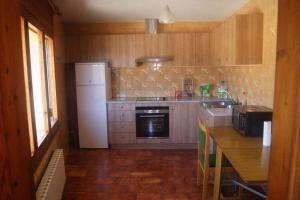 a kitchen with a white refrigerator and a table with chairs at Alpens Holidays Ca la Cèlia in Alpens