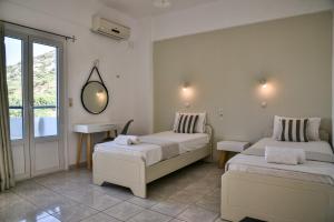 a bedroom with two beds and a mirror on the wall at Iraklis Apartments in Stalida