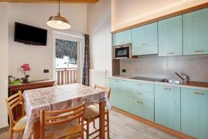 eine Küche mit blauen Schränken und einem Tisch mit Stühlen in der Unterkunft Casa Nicoletta estate in Livigno