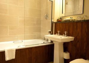 a bathroom with a sink and a bath tub and a sink at Whitley Hall Hotel in Chapeltown