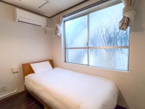 a small bedroom with a white bed and a window at Ishigakijima Hotel Olive in Ishigaki Island