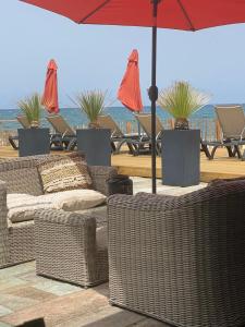 - un groupe de chaises en osier et de parasols sur une plage dans l'établissement Mariana Plage, à La Marana