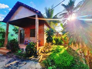 una pequeña casa con el sol brillando detrás de ella en Cat Tien Farmer Lodge, en Quan Tom