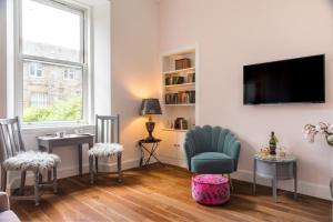 sala de estar con 2 sillas y TV en Newly renovated stunning apartment in Stockbridge, en Edimburgo