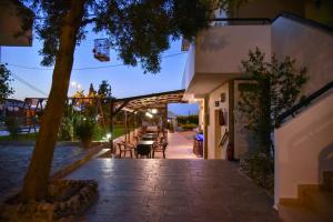 un patio con mesa, sillas y un árbol en Iraklis Apartments, en Stalida