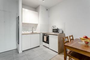 une cuisine avec des placards blancs et une table en bois dans l'établissement Chill Apartments Airport Apartments, à Varsovie