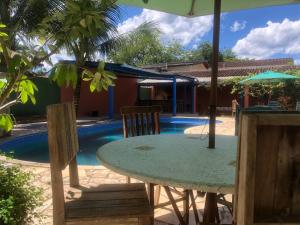 einen Tisch mit Stühlen und einen Sonnenschirm neben einem Pool in der Unterkunft A casa di Maria in Ubatuba