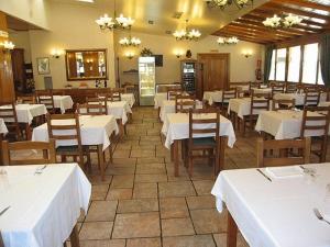 un comedor con mesas blancas y sillas de madera en Hostal Lorentxo, en Olave