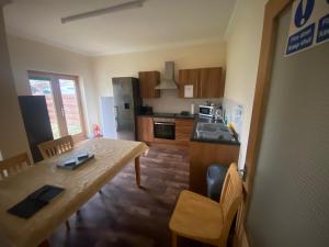 a kitchen with a wooden table and a dining room at Little Ship Inn Rooms in Invergordon