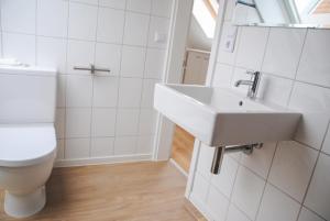 ein weißes Badezimmer mit Toilette und Waschbecken in der Unterkunft Groot Huus in Norderney + 15 Fotos