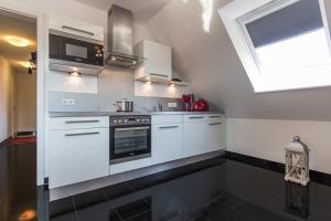 诺德奈Ferienwohnung Gertrud Wohnung 4的配有白色橱柜和微波炉的厨房 更多2张照片