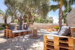 a patio with two benches and a table and trees at Casa Petit Paraiso in Lagoa