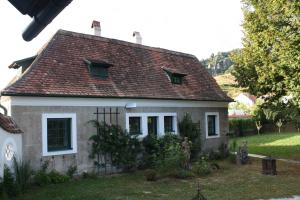 una pequeña casa blanca con techo marrón en Bioweingut Schmidl Rosenstöckel, en Dürnstein