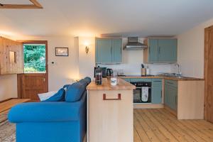 a kitchen with blue cabinets and a blue couch at Pheasants Lodge by Bloom Stays in Canterbury