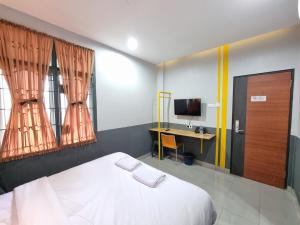 sypialnia z łóżkiem, biurkiem i telewizorem w obiekcie Super OYO Capital O 90874 Millenium Inn 2 w mieście Medan
