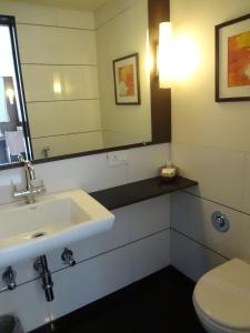 a bathroom with a sink and a toilet and a mirror at Shantai Hotel in Pune