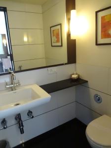 a bathroom with a sink and a toilet and a mirror at Shantai Hotel in Pune
