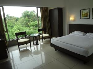 a bedroom with a bed and a table and a window at Shantai Hotel in Pune