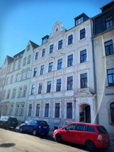 a red car parked in front of a large building at Ferienwohnung am Busbahnhof in Annaberg-Buchholz