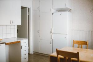 uma cozinha com armários brancos, uma mesa e um frigorífico em Lappland Pro Natur em Åsele
