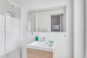 a white bathroom with a sink and a mirror at Freedomus Marne-la-Vallée "Le 12" in Crecy la Chapelle