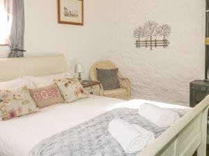 利斯卡德的住宿－Nightingale Cottage，卧室配有带枕头和椅子的白色床