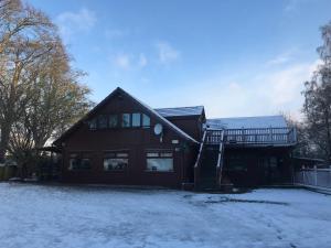 a house with snow on the ground in front of it at Pine Chalet in Muir of Ord