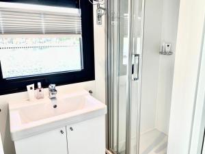 ein weißes Bad mit einem Waschbecken und einer Dusche in der Unterkunft Houseboat Earebarre - Waterrijck Sneekermeer, Sneek - Offingawier in Offingawier