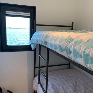 ein Schlafzimmer mit einem Etagenbett und einem Fenster in der Unterkunft Houseboat Earebarre - Waterrijck Sneekermeer, Sneek - Offingawier in Offingawier