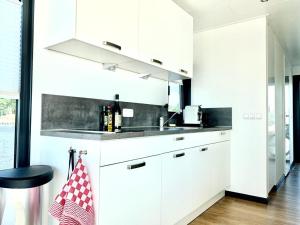 una cocina con armarios blancos y fregadero en Houseboat Earebarre - Waterrijck Sneekermeer, Sneek - Offingawier, en Offingawier